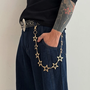 Gold star trouser chain with hollow pentagram links on dark blue jeans for streetwear