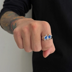 Detail shot of a silver star ring with blue enamel inlay worn on a male hand