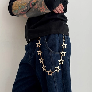 Detail view of a gold hollow star waist chain accessory styled on blue denim jeans