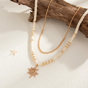Close-up of double-layer coconut bead necklace with golden sun pendant on white sand