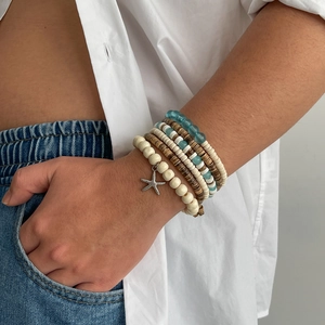 Detail of layered bohemian bead bracelets with coconut wood beads and a silver starfish charm