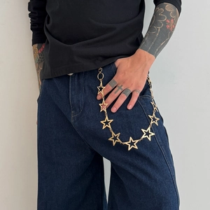 Close-up of golden star chain pant accessory on dark denim jeans for hip hop style
