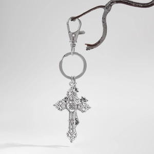 Gothic silver cross keychain with lobster clasp hanging on a branch macro detail view