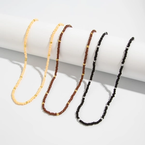 Detail of four handmade beaded necklaces in beige, red, brown and black on white stand