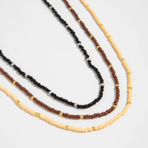 Detail view of handmade beaded necklaces in black, chocolate brown, and beige with metal spacers