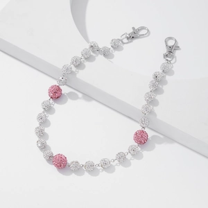 Détail de perles serties de cristaux roses et argentés sur une chaîne de pantalon chic