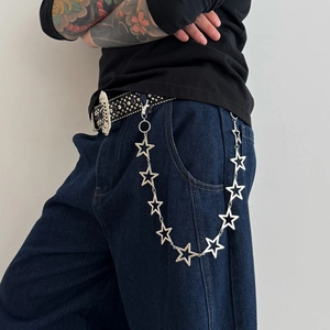 Detail of silver pentagram metal pant chain with stars on black rivet belt and denim jeans
