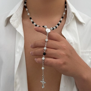 Macro shot of hip hop rosary necklace with black beads, silver sphere, and cross pendant