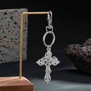 Macro view of vintage silver cross keychain with embossed details on rock background