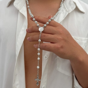Detail of silver iced-out hip hop rosary with cross pendant and crystal beads on model