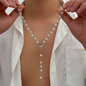 Detail of silver iced-out disco ball chain necklace with medallion on a white shirt