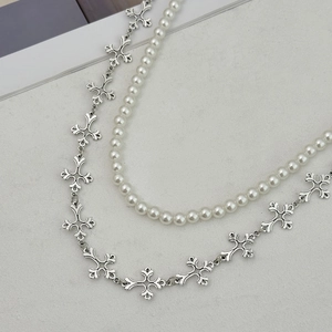 Detail of layered white pearl necklace and vintage silver cross link chain for men