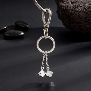 Détail d'un pendentif dé en métal argenté avec chaîne torsadée et porte-clés mousqueton