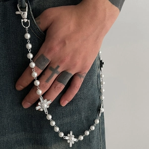 Detail of hip hop trouser chain with white pearls and cross pendants on denim jeans