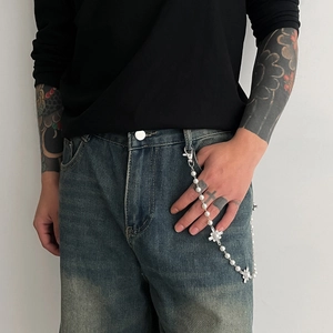 Detail of pearl cross pants chain with silver pendants on vintage denim jeans
