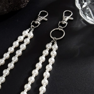 Détail d'une chaîne de jean en perles avec fermoir mousqueton argenté sur une surface noire