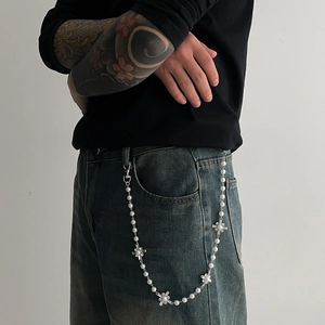 Close-up of hip hop style pants chain with white pearls and silver cross pendants on jeans
