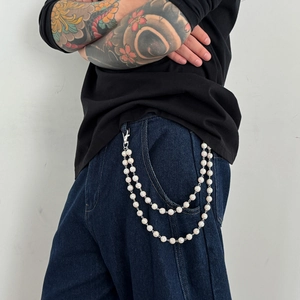 Detail of double-layer silver hip-hop chain with pave crystal balls on blue jeans