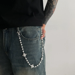 Detailed view of pearl pant chain with sparkling rhinestone cross pendants on denim