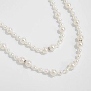 Détail de perles d'imitation avec des espaceurs métalliques sertis de cristaux fins