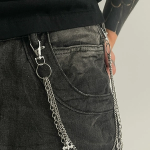 Detail shot of multi-layer silver metal pants chain with a cross pendant on denim