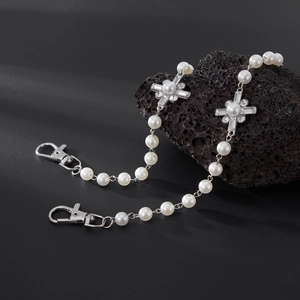Close-up of pearl waist chain with silver diamond-encrusted crosses on volcanic stone