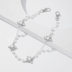 Macro detail of pearl waist chain with silver cross charms and lobster clasps