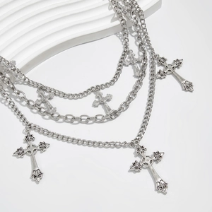 Detail of layered silver metal chains with gothic cross pendants and punk style textures