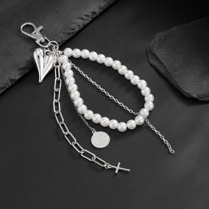 Macro detail of industrial silver metal clasp with pearl beads and heart cross pendants