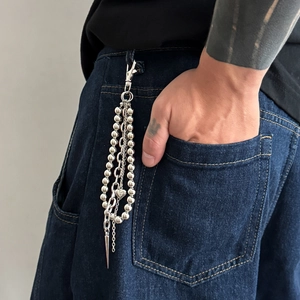 Detail of multi-layered silver metal wallet chain with heart and cone charms on jeans