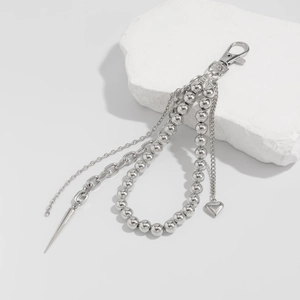 Detailed close-up of multi-layer silver metal keychains with heart and cone pendants