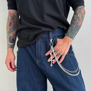 Close-up of multi-layered silver cross pendant hip-hop waist chain on denim jeans