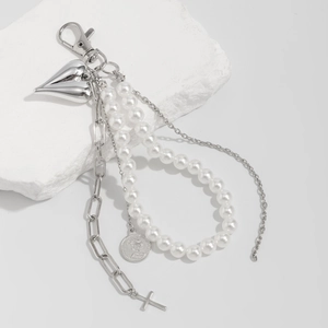 Detail of silver heart, pearl beads and cross charms on a stylish multi-element keychain
