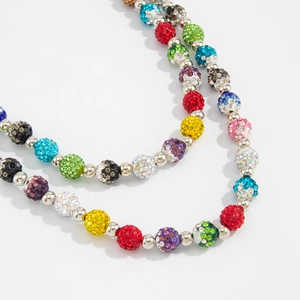 Macro detail of colorful rhinestone disco ball beads on a hip-hop style silver metal waist chain