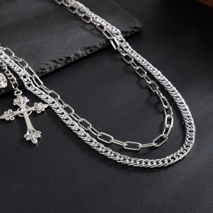 Close-up of double-layered silver cross chain with retro textures and gothic skull accents