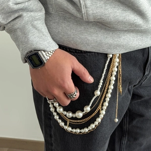Detail of layered pearl tassel pants chain with gold cone pendant and hip hop style