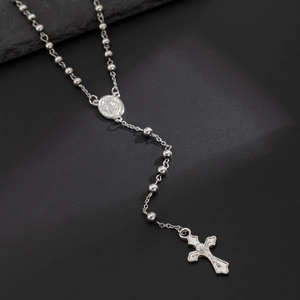Vue macro d'une chaîne à billes argentée avec médaillon religieux et pendentif croix