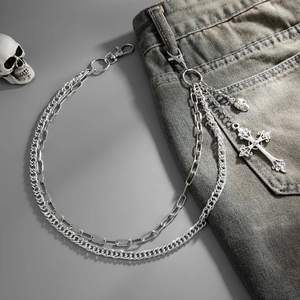 Detail of silver multi-layer punk chain with cross and skull charms on denim jeans