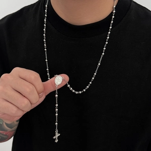 Gros plan sur collier chapelet argenté avec perles rondes et médaille religieuse sur mannequin