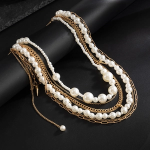 Macro shot of gold metal chain and white pearls showing layered luxury hip-hop jewelry style