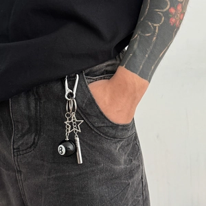 Macro detail of a silver keychain with Black 8 billiard ball and star pendant on jeans