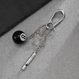 Close-up of black 8 billiard ball charm with metallic star and whistle on a key ring