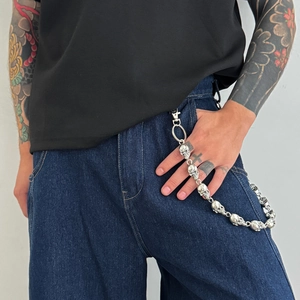 Détail d'une chaîne de pantalon tête de mort argentée avec fermoir sur un jean bleu