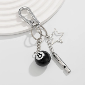 Detail of silver carabiner keychain with number 8 billiard ball, star, and whistle