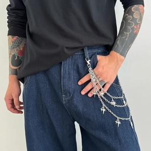 Detail view of multi-layered silver metal pants chain with Y2K star pendants on jeans