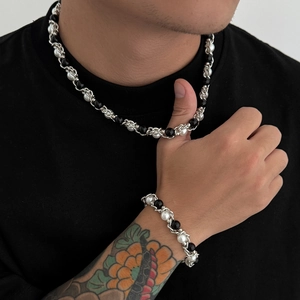 Detail van een zilveren ketting met gevlochten witte parels en zwarte glanzende kralen