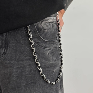 Detail shot of silver metal rings and black beads hip hop wallet chain on jeans