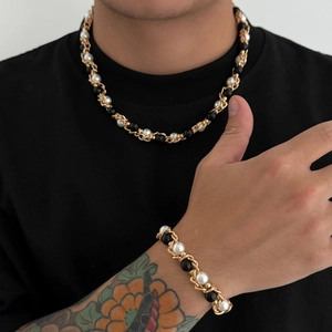 Detail van goudkleurige ketting en armband set met tweekleurige parels op een mannelijk model