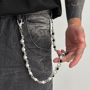 Detail of silver hip-hop chain with black and white pearls on distressed jeans