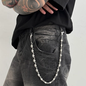 Close-up of street style hip-hop waist chain with silver links and white pearls on denim